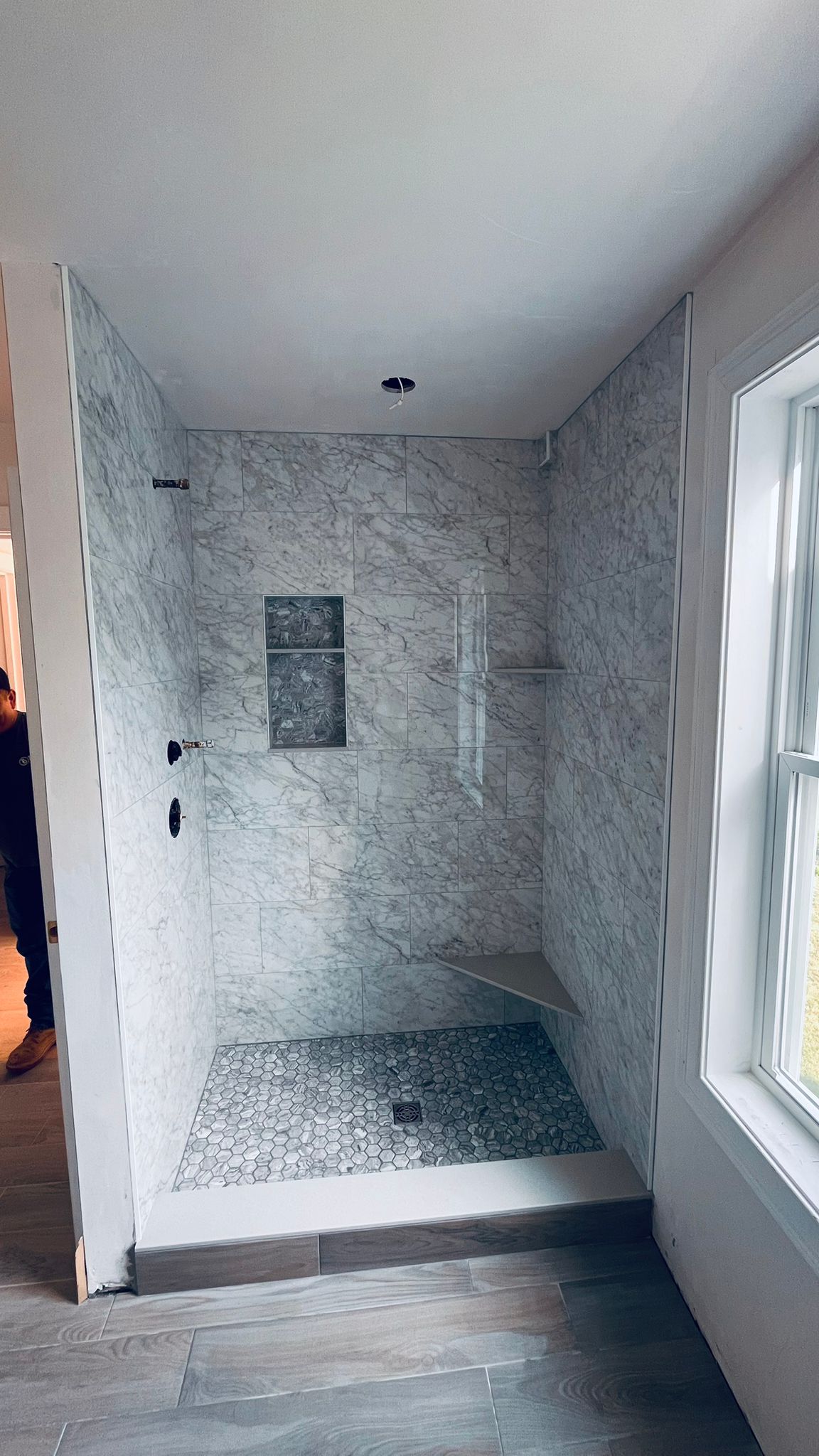 Carrara marble shower with a built-in tiled bench
